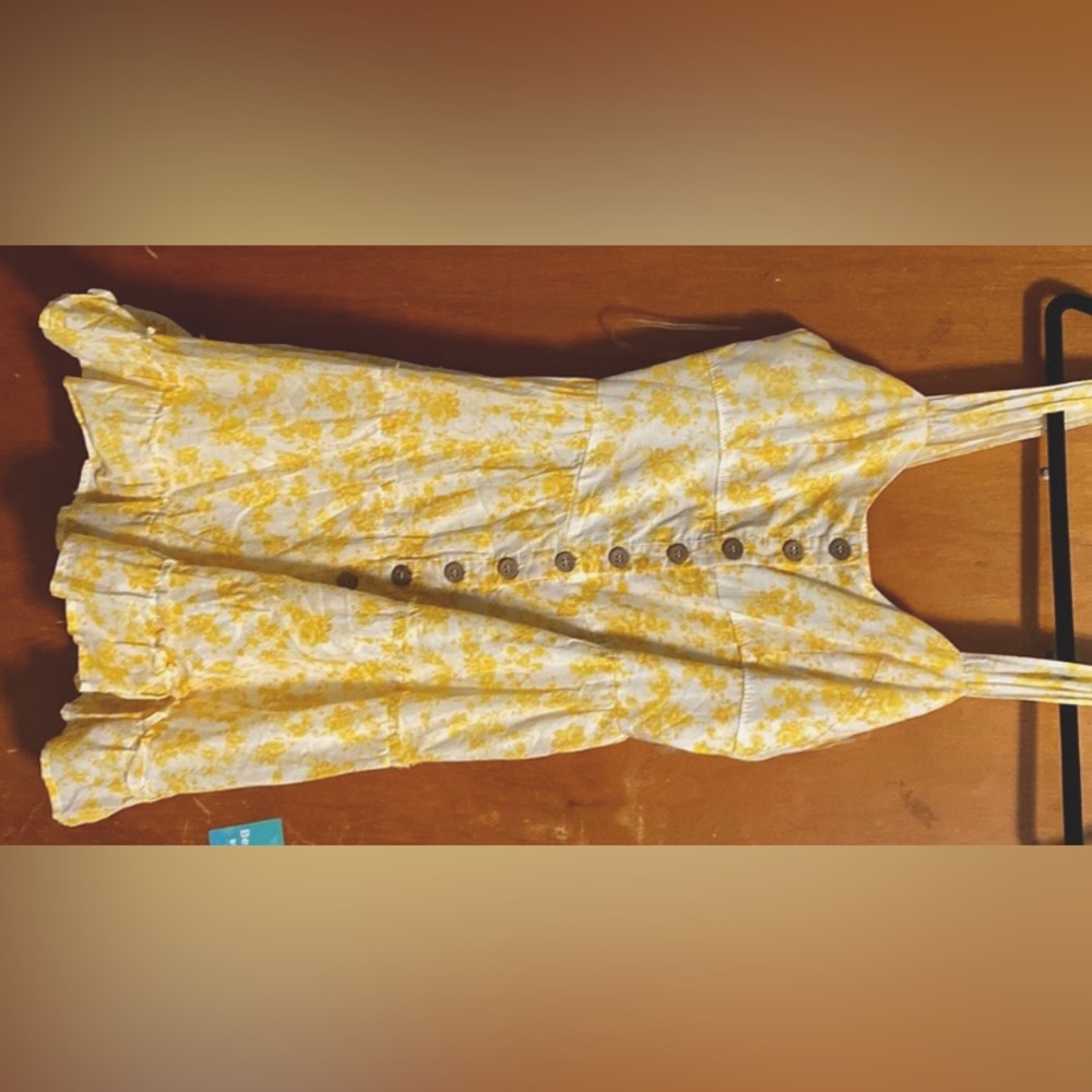 White dress with yellow flowers. Wooden buttons down the middle